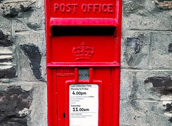 Photo of a Red UK post box in a wall.